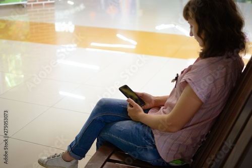 a young girl is resting in the mall and looking into the phone