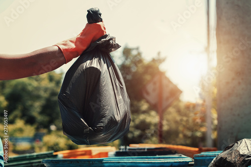 hand holding garbage black bag putting in to trash photo