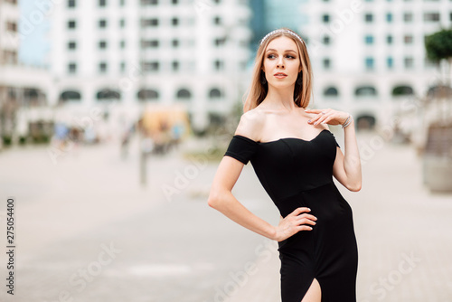 beautiful young girl in black dress walking the streets of the city, the woman is resting outdoors, street fashion. urban lifestyle.