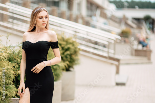 beautiful young girl in black dress walking the streets of the city, the woman is resting outdoors, street fashion. urban lifestyle.