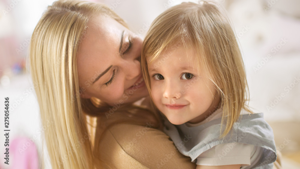 Portrait Shot of a Young Beautiful Mother Holding Her Little Cute Daughter In Her Arms. They Smile into the Camera.