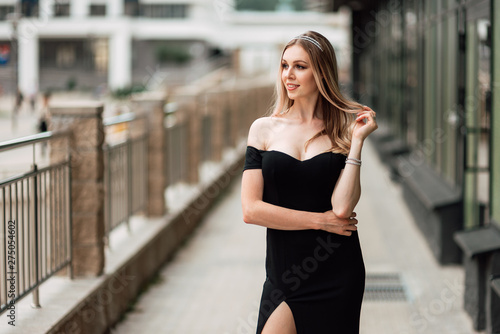 beautiful young girl in black dress walking the streets of the city, the woman is resting outdoors, street fashion. urban lifestyle.