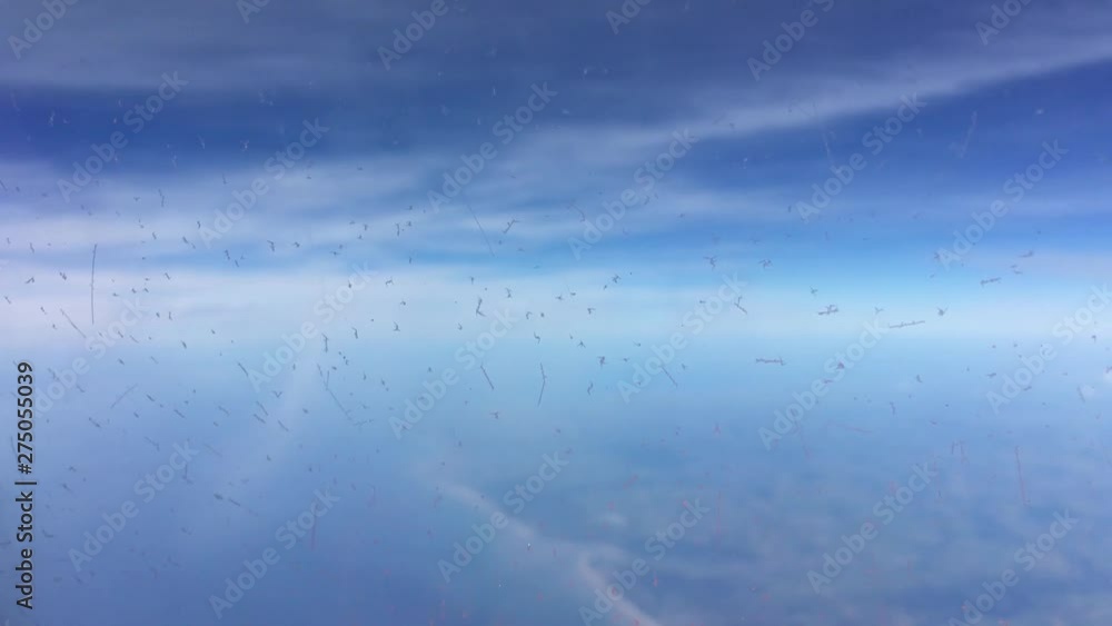 A flight over the white clouds with blue sky and ice crystals on the window A flight over the white clouds with blue sky and ice crystals on the window
