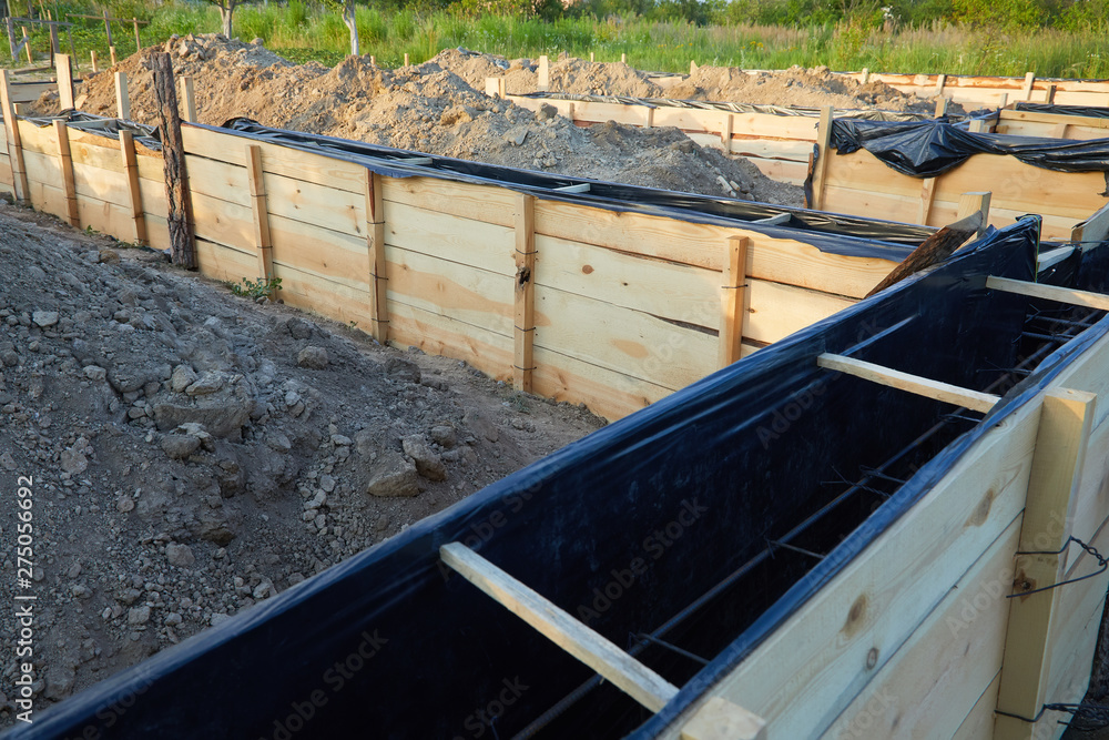 Wooden formwork concrete strip foundation for a cottage. Foundation site of new house, building, details and reinforcements with steel bars and wire rod, preparing for cement pouring