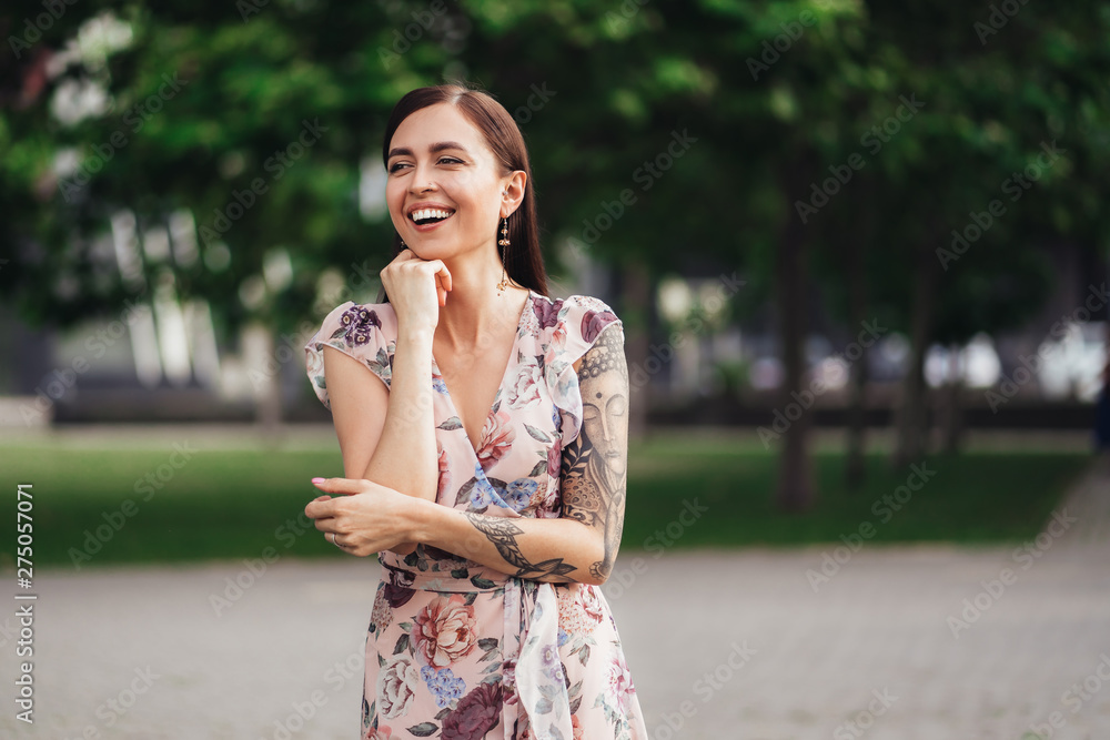 Laughing girl in dress with tattoo on her hands posing of greenery on background Laughing girl in dress with tattoo on her hands posing of greenery on background