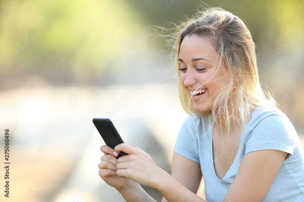 Happy teenage girl checking phone content in a park Happy teenage girl checking phone content in a park