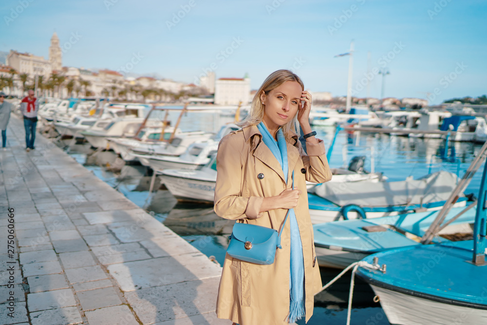 Young traveling woman in coat walking on Split promenade sea embankment enjoying the view. Young traveling woman in coat walking on Split promenade sea embankment enjoying the view.