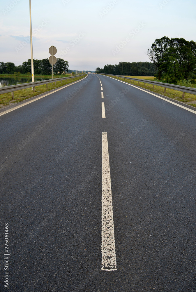 Fototapeta premium Photo of dark asphalted road and metall barrier