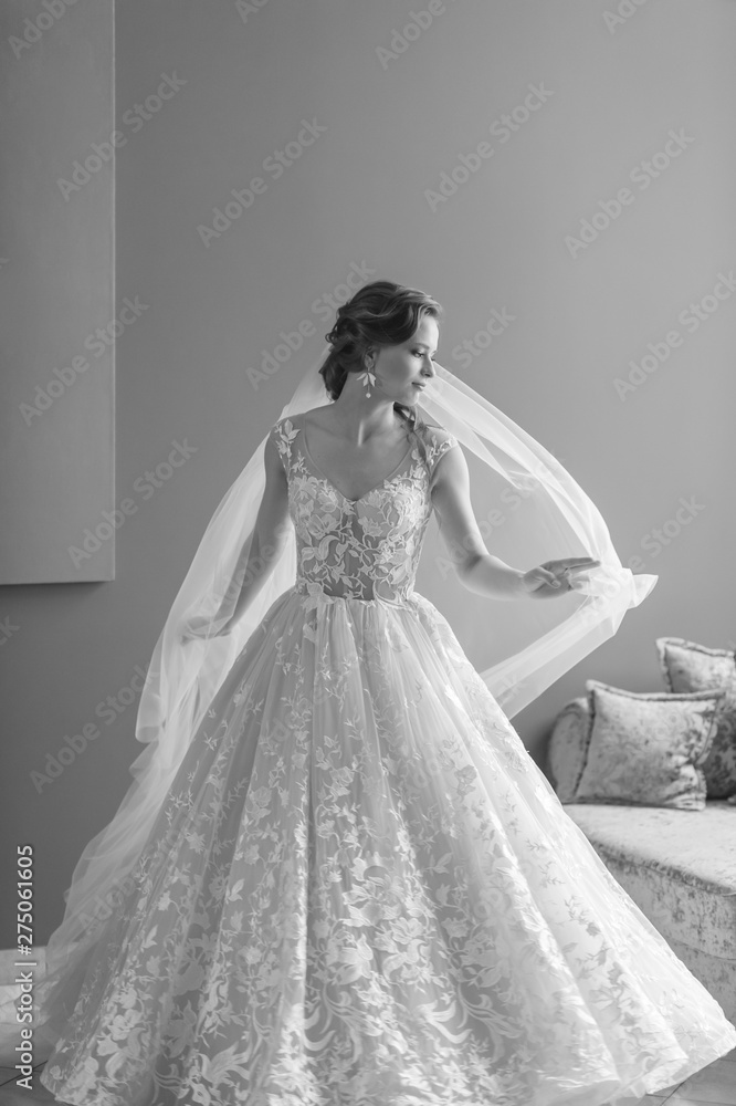 Black and white portrait of beautiful bride in wedding dress touchs and throws her veil up in hotel. Black and white portrait of beautiful bride in wedding dress touchs and throws her veil up in hotel.