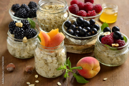 Oat flakes with various berries, hazelnuts and honey in glass jars