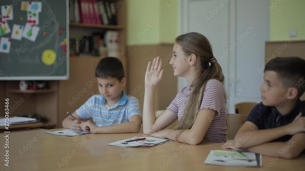 Education, elementary school. Learning and people concept - group of school kids with pens and notebooks writing test in classroom Education, elementary school. Learning and people concept - group of school kids with pens and notebooks writing test in classroom