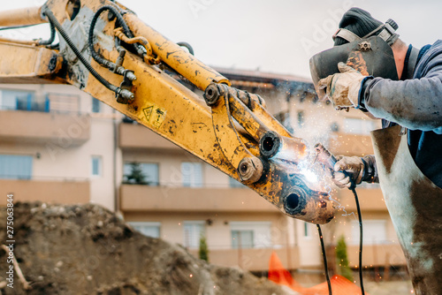 Close up of mechanic fixing excavator on construction site