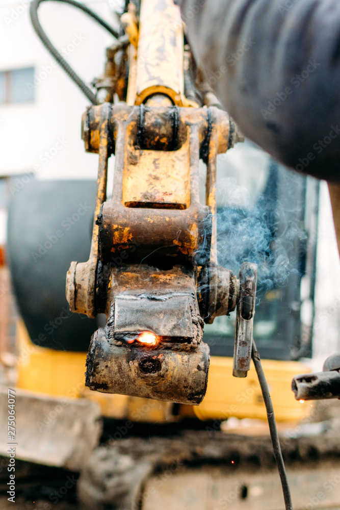 Broken excavator on construction site, repairing and fixing arm