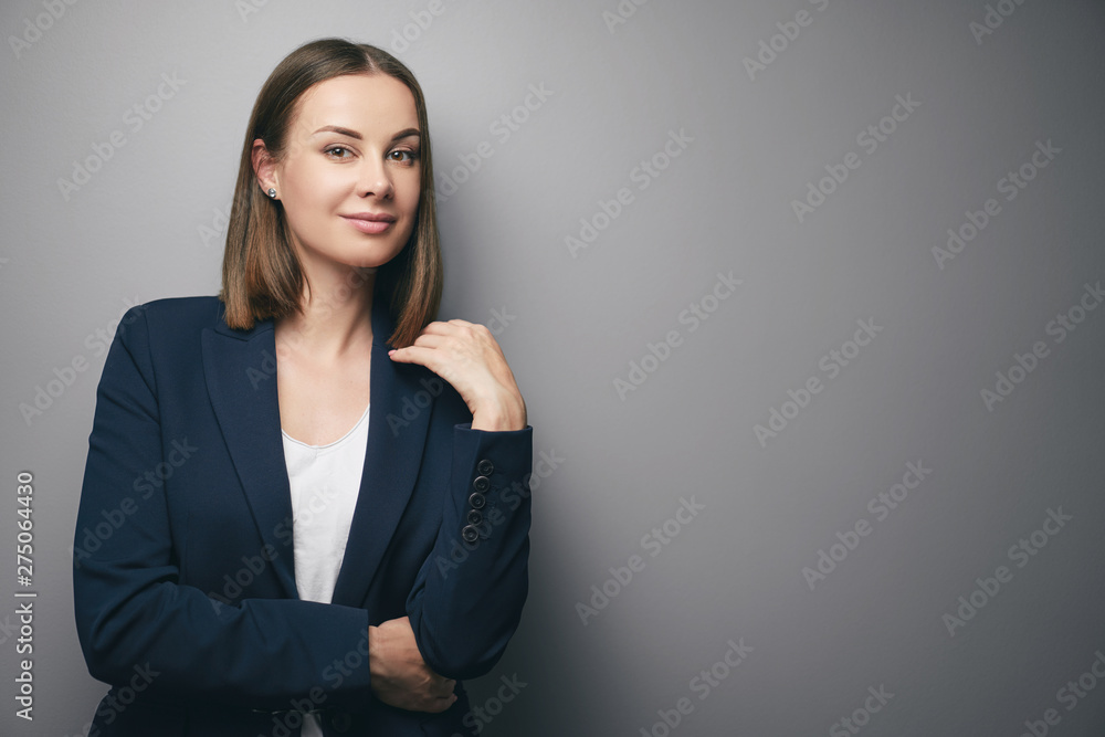 Confident young business woman in suit looking at camera. Grey background with copy space. Confident young business woman in suit looking at camera. Grey background with copy space.