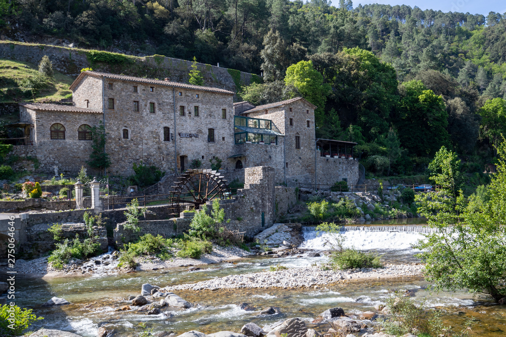 Eine historische Herberge in den französischen Cevennen mit einem Fluss und einem Wehr im Vordergrund