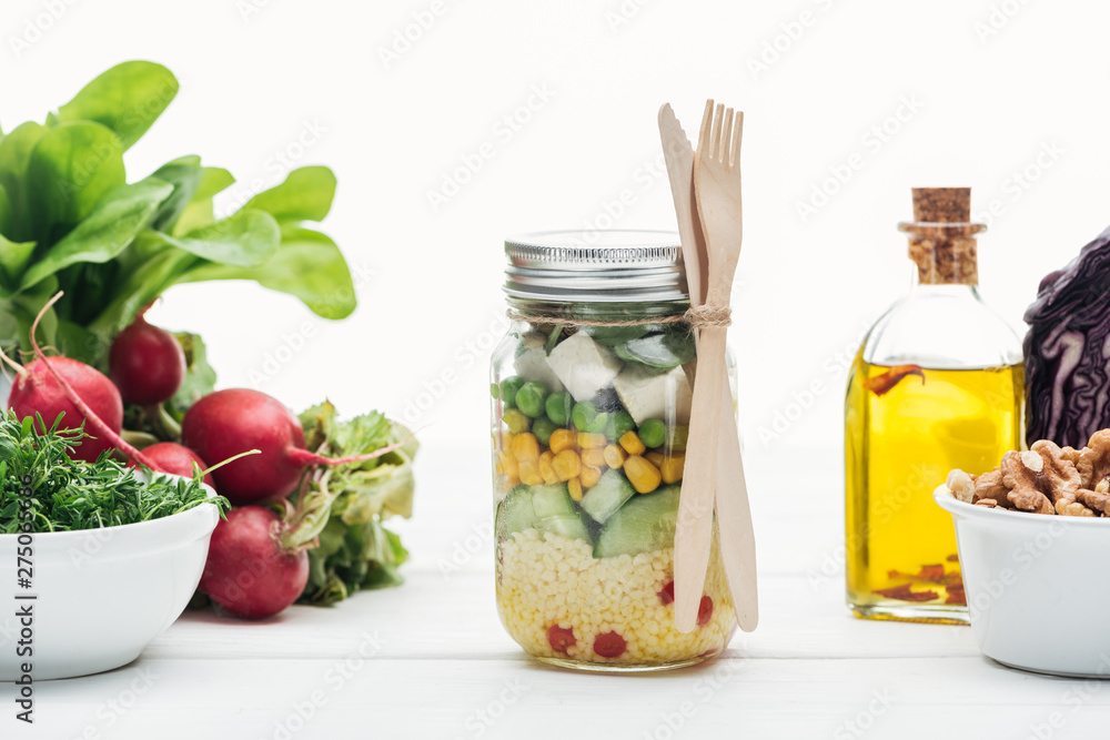 fresh vegetable salad in glass jar near oil and radish isolated on white fresh vegetable salad in glass jar near oil and radish isolated on white