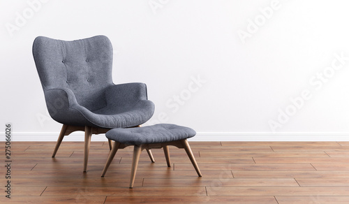 Fashionable modern gray armchair with wooden legs, ottoman against a white wall in the interior. Furniture, interior object, modern designer armchair. Stylish minimalist interior