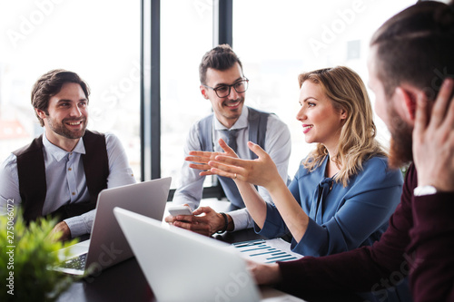 Photography A group of young business people with laptop sitting in an office, talking