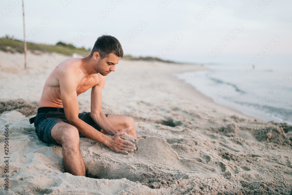 Man on the beach building sand castle.