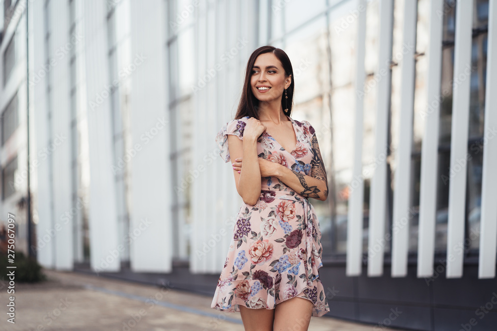 Beautiful happy young woman in colored dress posing near business center Beautiful happy young woman in colored dress posing near business center