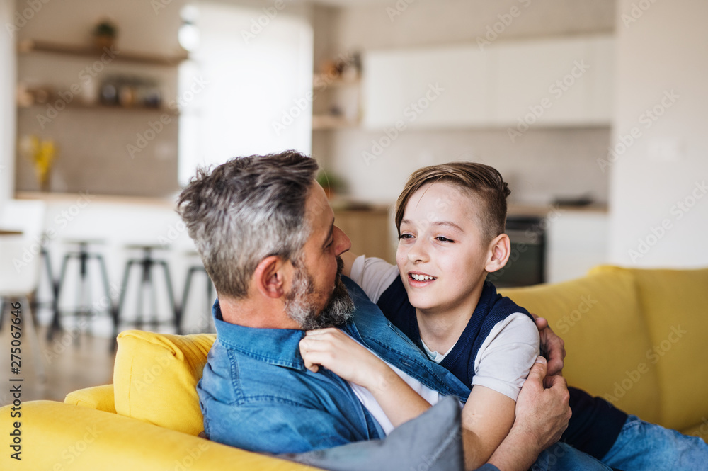Mature father with small son sitting on sofa indoors, resting. Mature father with small son sitting on sofa indoors, resting.