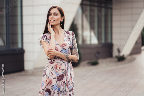 Beautiful young woman in colored dress posing near business center