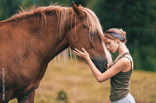 Young beautiful girl hugging horse at nature. Horse lover.