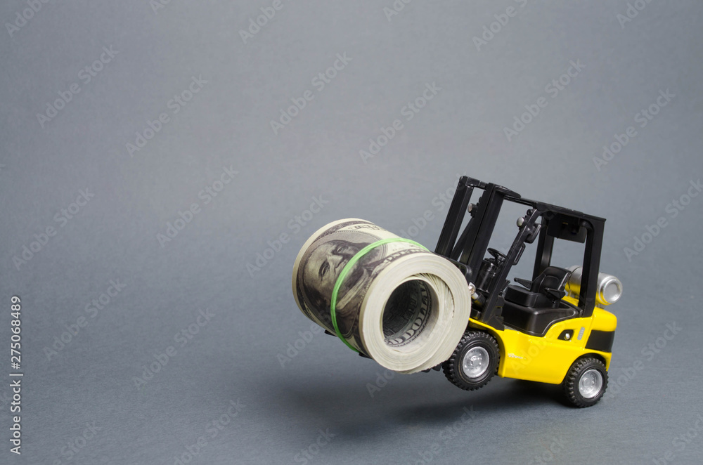 A yellow loader stands on the rear wheels holding a big bundle of dollars. concept of attracting investment, issuing concessional loans for business development. High profitability of stocks and bonds A yellow loader stands on the rear wheels holding a big bundle of dollars. concept of attracting investment, issuing concessional loans for business development. High profitability of stocks and bonds