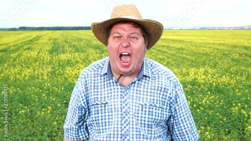 Farmer standing in field and screaming in horror or evil, in hat on a sunny day