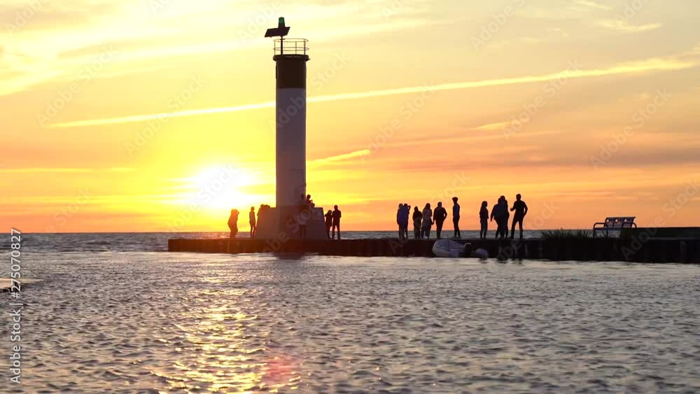 Sun setting over pier in grand bend with silhouettes of people watching