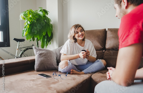 A couple talks and drinks coffee on the couch at home photo