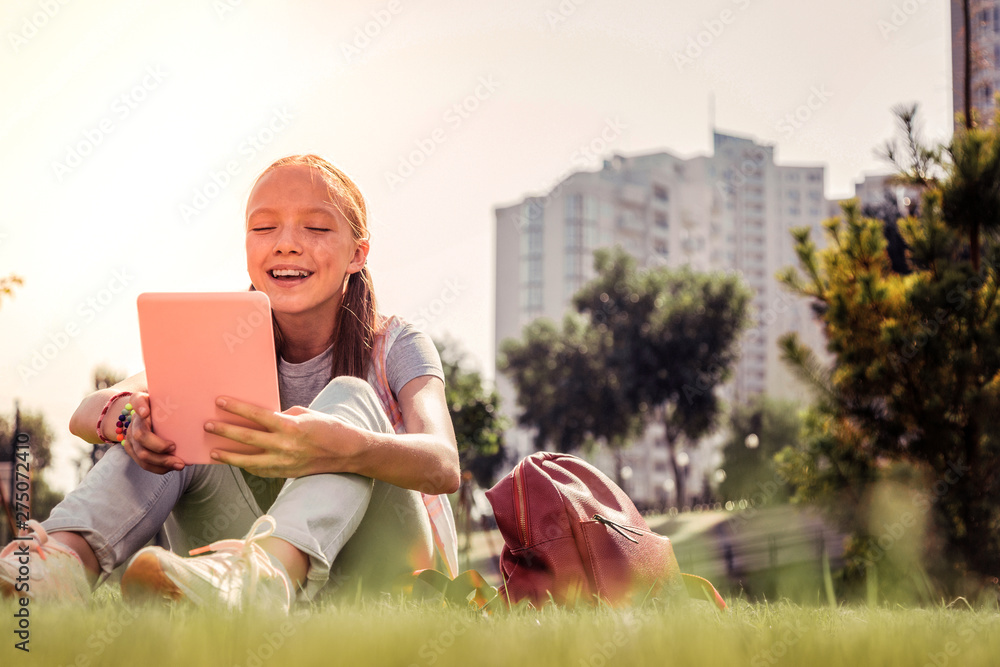 Laughing good-looking girl being entertained with content in a tablet