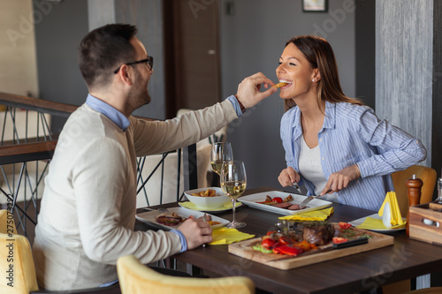 Couple tasting each other's food in restaurant