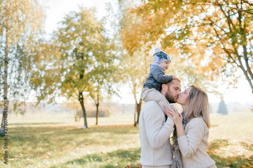 Happy family with their baby outdoor portrait. Father holding his little boy on shoulders.