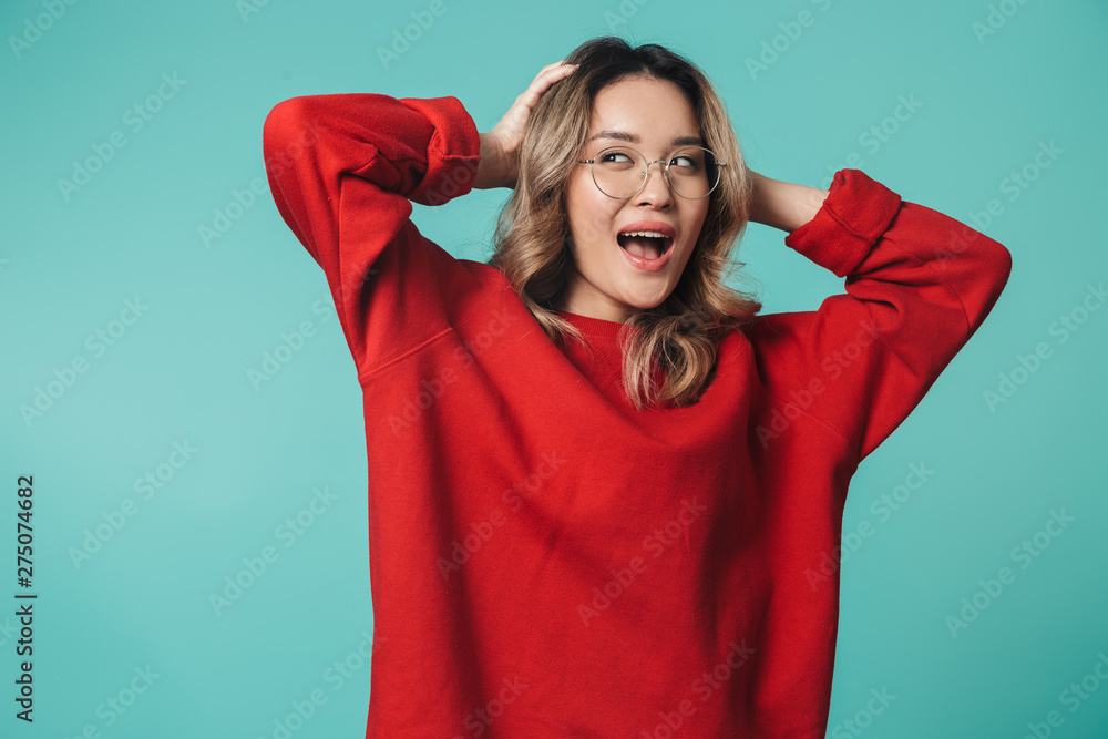 Happy cute young woman posing isolated over blue wall background. Happy cute young woman posing isolated over blue wall background.