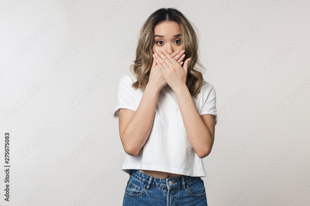 Shocked emotional cute young woman posing isolated over white wall background. Shocked emotional cute young woman posing isolated over white wall background.