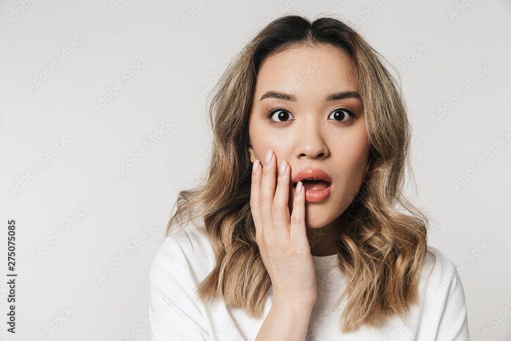Shocked emotional cute young woman posing isolated over white wall background. Shocked emotional cute young woman posing isolated over white wall background.