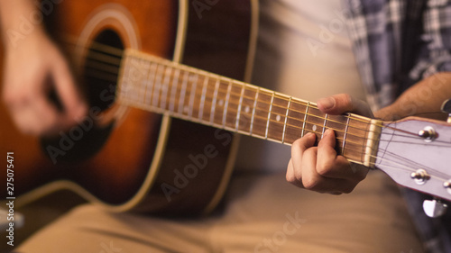 Man plays guitar while rehearsing a song in a home studio in a garage.
