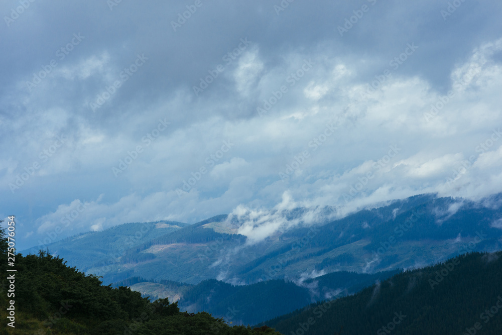 Clouds over the mountain covered with green trees