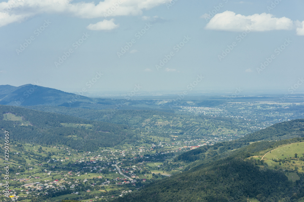 Fototapeta premium Aerial view of green mountain valley with town