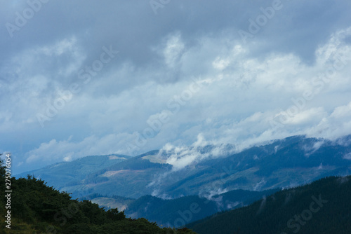 Fototapeta Naklejka Na Ścianę i Meble -  Clouds over the mountain covered with green trees