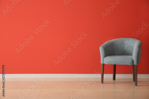 Comfortable armchair near color wall in room