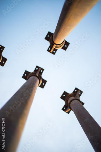 Four metallic pillars pointing the sky show from below during day photo