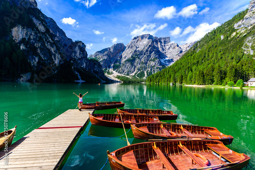 Woman relaxing on Pier at Lake Braies also known as Pragser Wildsee in beautiful mountain scenery. Amazing Travel destination Lago di Braies in Dolomites, South Tyrol, Italy, Europe.