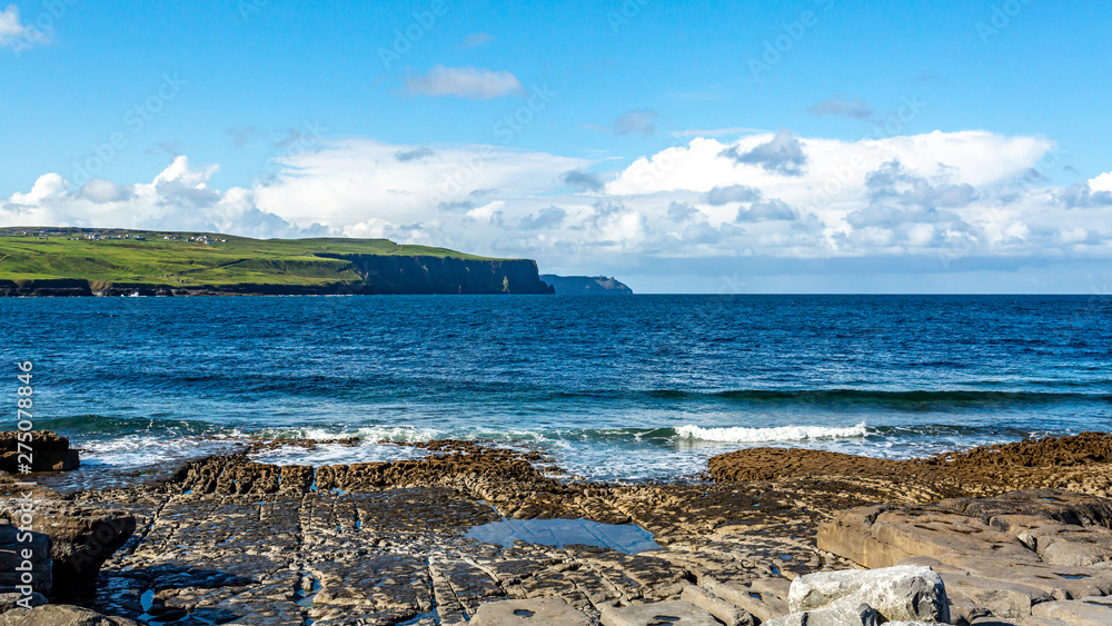 Doolin Bay with the Cliffs of Moher in the background on a beautiful sunny spring day, Wild Atlantic Way, blue sky and white clouds on a calm day in County Clare in Ireland