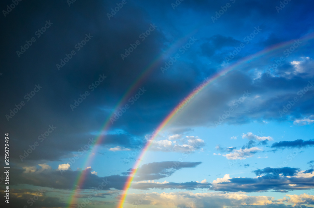 The sky in the clouds and with a double rainbow after the summer thunderstorm. Amazing dramatic clouds texture, background image. The sky in the clouds and with a double rainbow after the summer thunderstorm. Amazing dramatic clouds texture, background image.