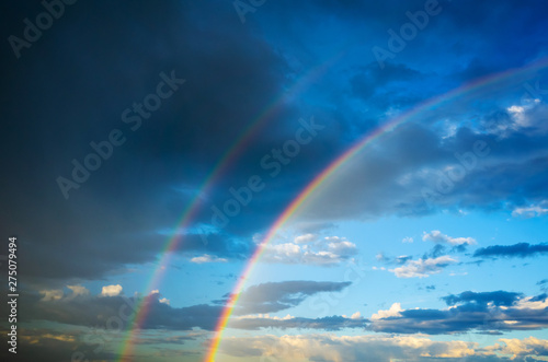 The sky in the clouds and with a double rainbow after the summer thunderstorm. Amazing dramatic clouds texture, background image.