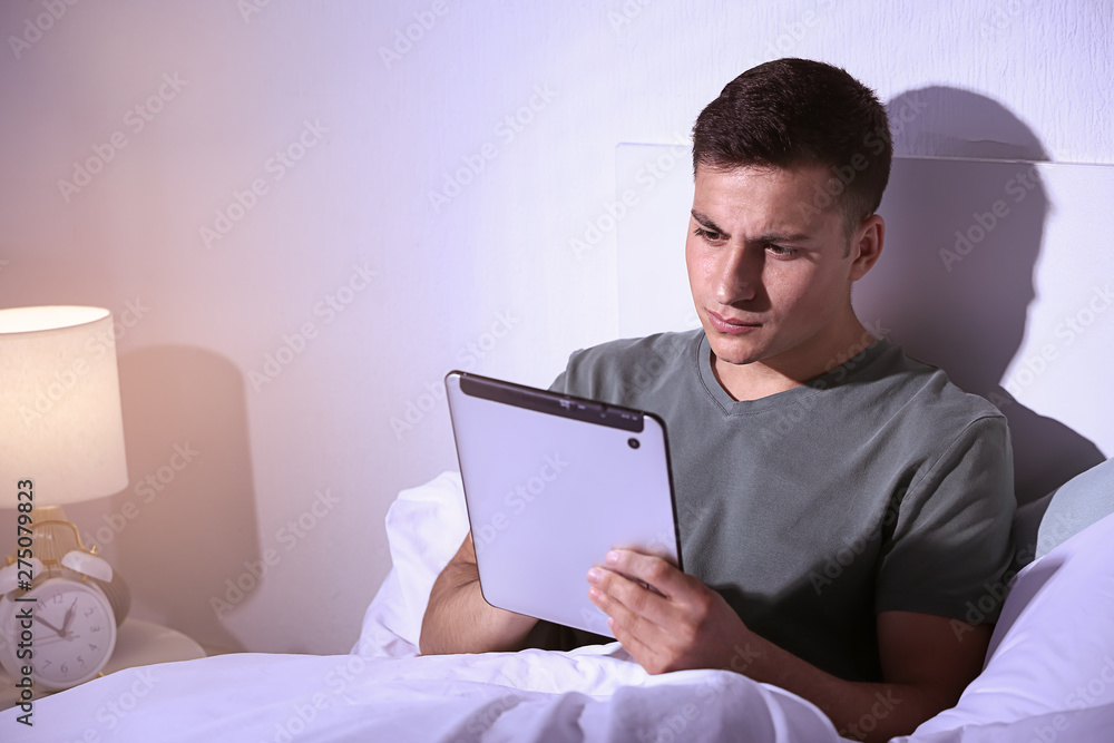 Young man with tablet computer in bed at night Young man with tablet computer in bed at night