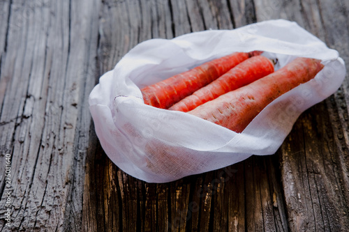 Raw fresh carrots in reusable cotton produce bags. Zero waste and no plastic concept. photo