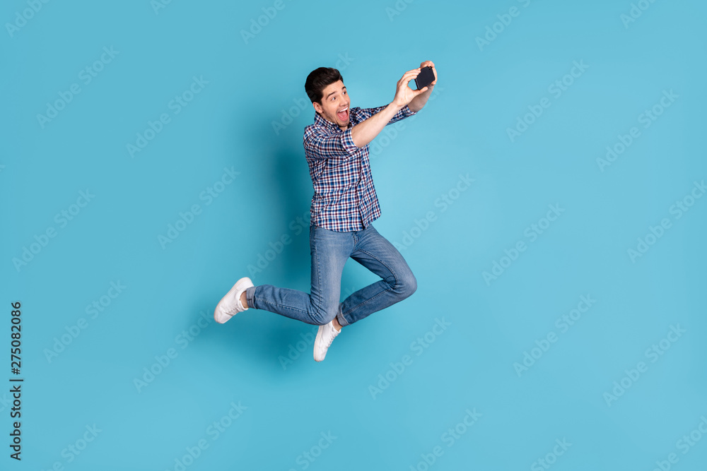 Ful length body size view photo charming youth make photo video call blog blogger social network shout expression summer weekends holidays checked shirt plaid jeans sneakers isolated blue background